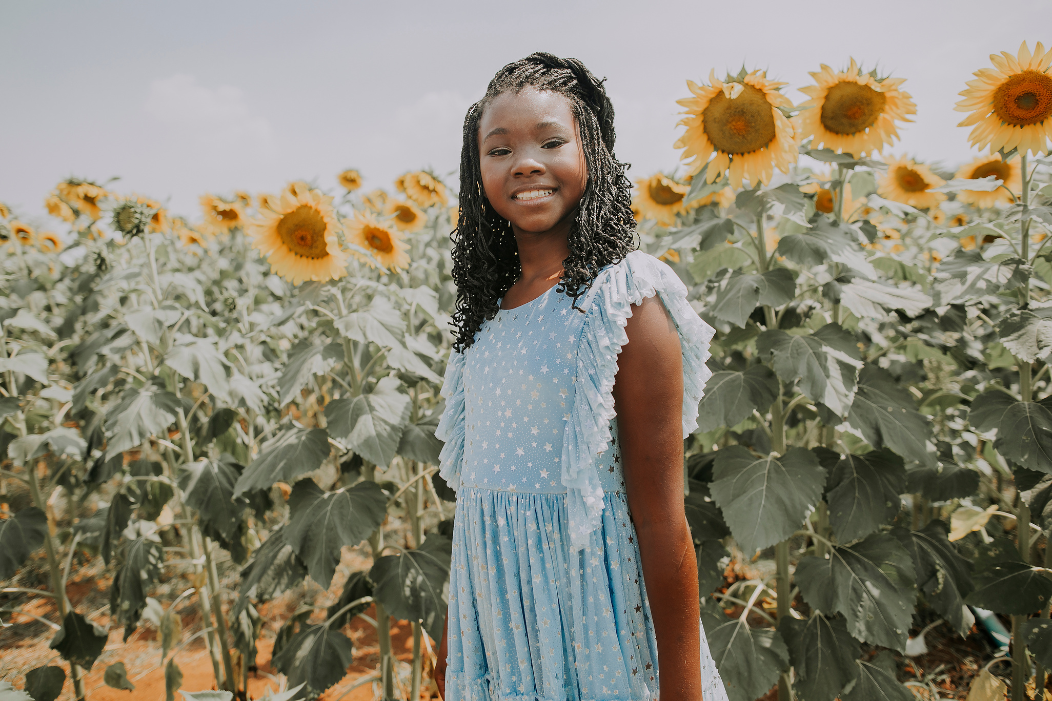 Happy black girl in field with sunflowers